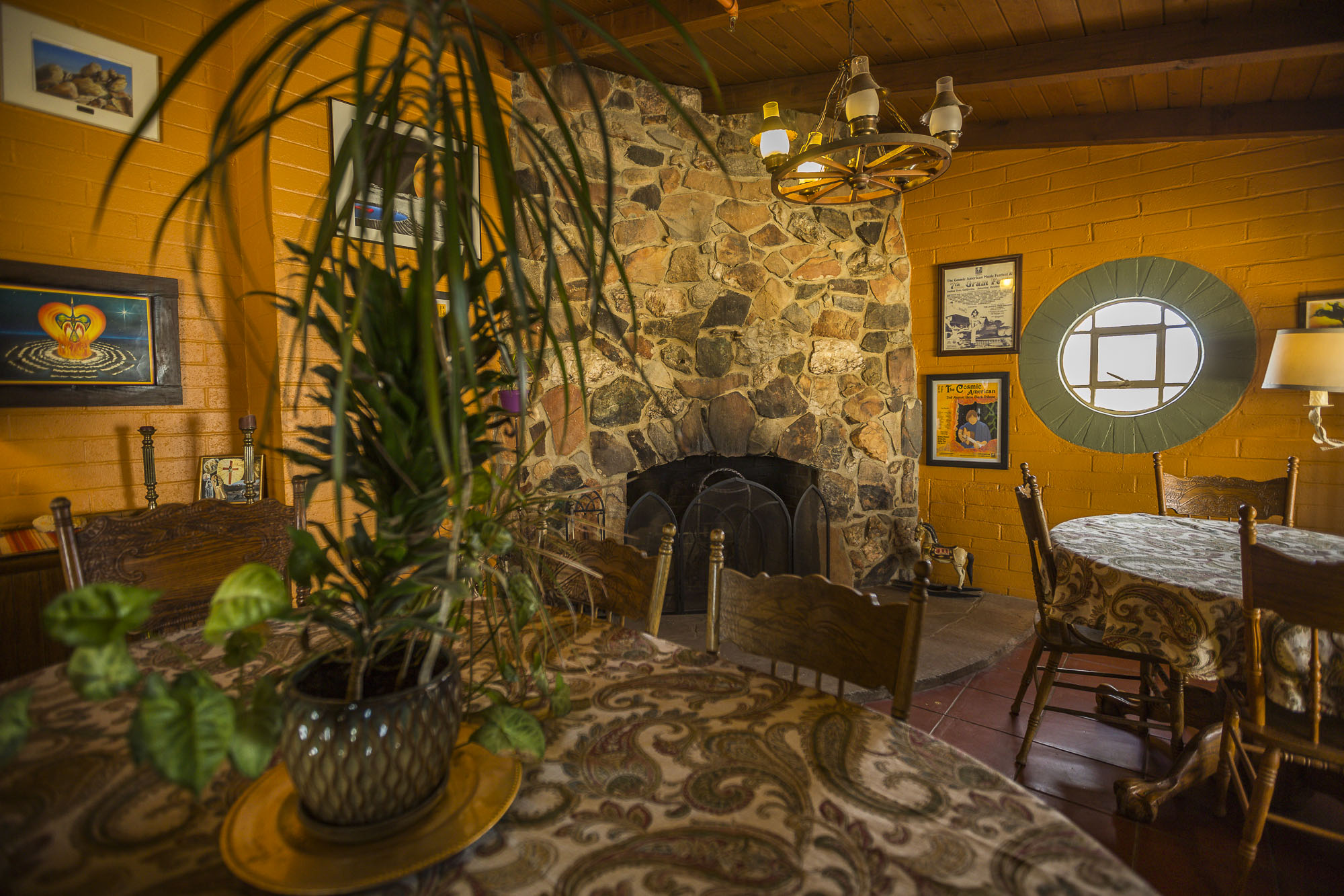 A comon rooms with potted plant on a dining room table and a fireplace in the backround.